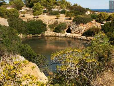 ...all�improvviso ci ritroviamo davanti a un panorama mozzafiato. Ci troviamo su un dirupo e sotto di noi si apre in tutta la sua bellezza il misterioso lago: un piccolo bacino di color verde intenso abbracciato da alte pareti rocciose e situato a pochi metri dallo sfondo azzurro del mare